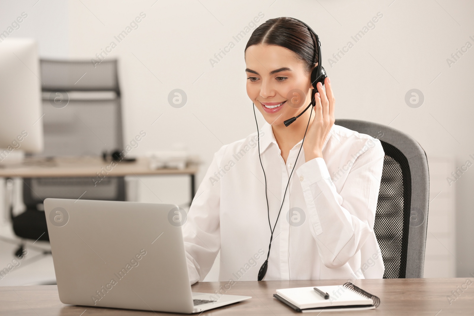 Photo of Hotline operator with headset working on laptop in office