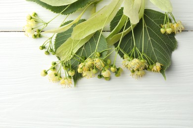 Photo of Fresh linden leaves and flowers on white wooden table, top view. Space for text