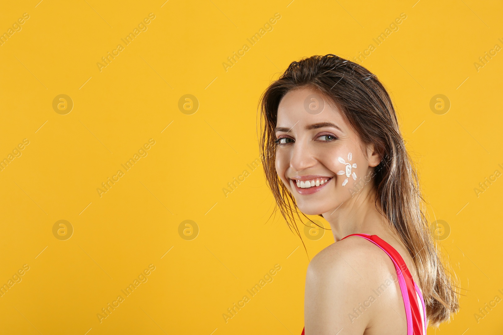 Photo of Young woman with sun protection cream on face against yellow background. Space for text