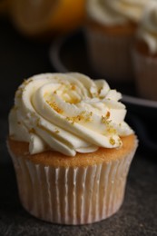 Photo of Delicious cupcake with white cream and lemon zest on table, closeup