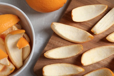 Photo of Many orange peels preparing for drying and fruit on grey textured table, flat lay