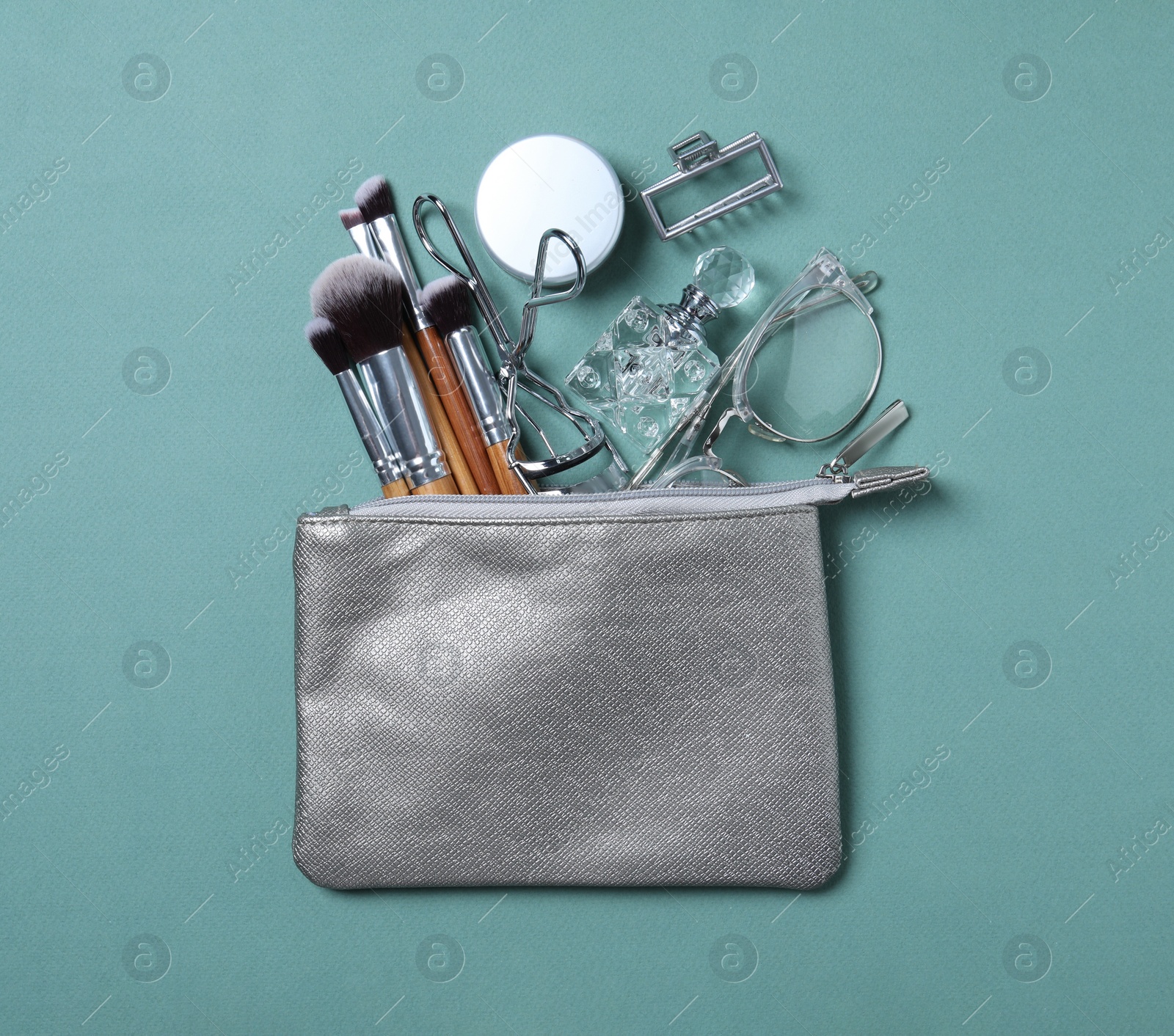 Photo of Cosmetic bag with makeup products and beauty accessories on blue-gray background, flat lay