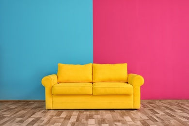 Photo of Yellow sofa near color wall in room