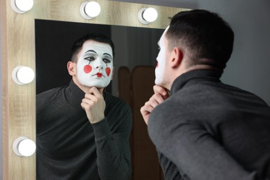 Photo of Mime artist posing near mirror in dressing room