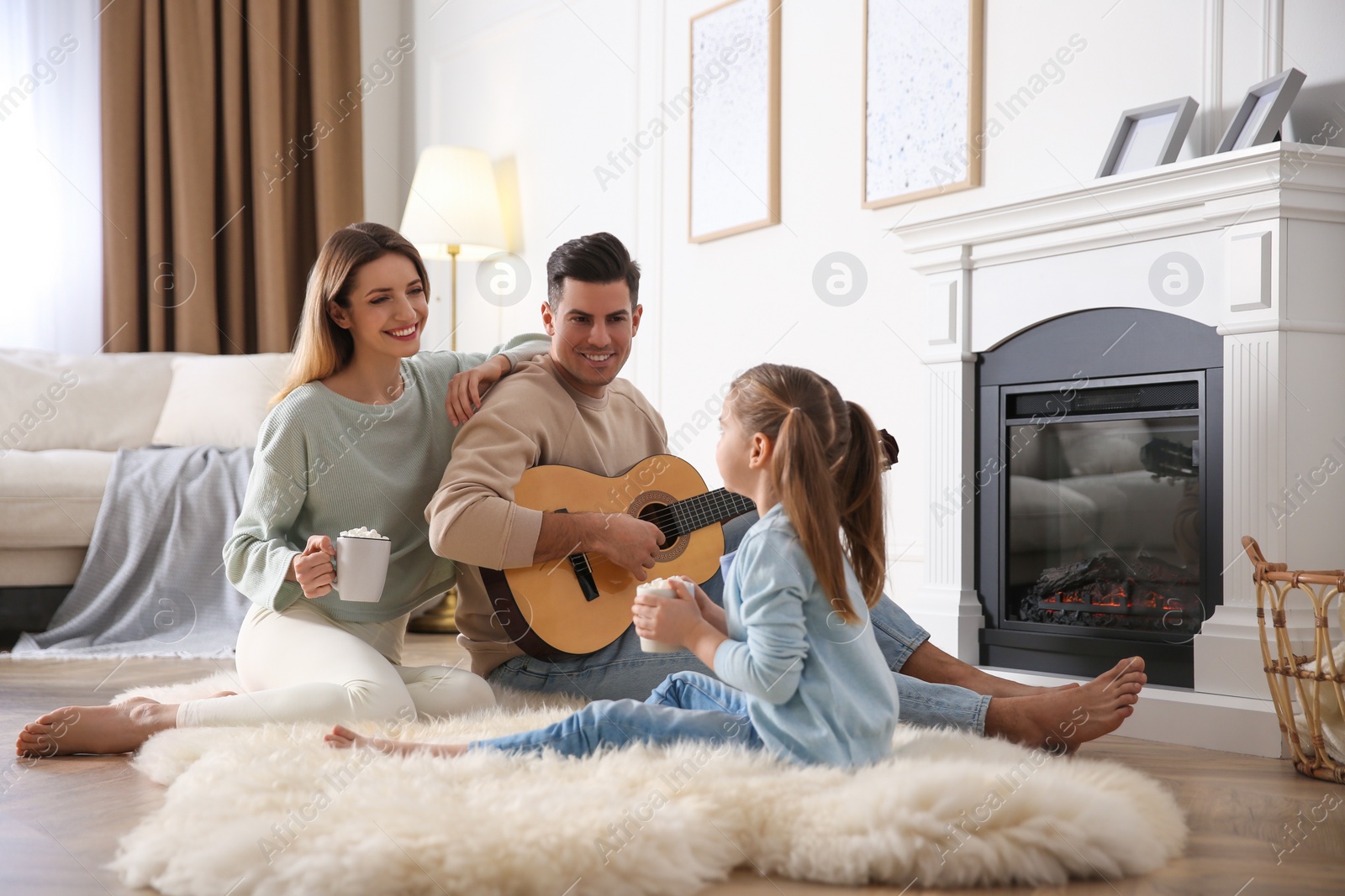 Photo of Happy family spending time together near fireplace at home