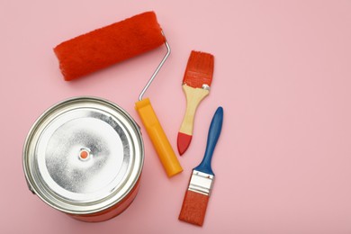 Photo of Bucket of orange paint, roller and brushes on pink background, flat lay. Space for text