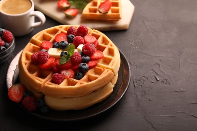 Tasty Belgian waffles with fresh berries, cheese and cup of coffee on black table, space for text