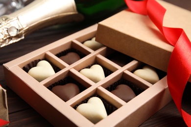 Photo of Tasty heart shaped chocolate candies on wooden table, closeup. Happy Valentine's day