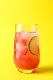 Tasty summer watermelon drink with lime in glass on yellow background