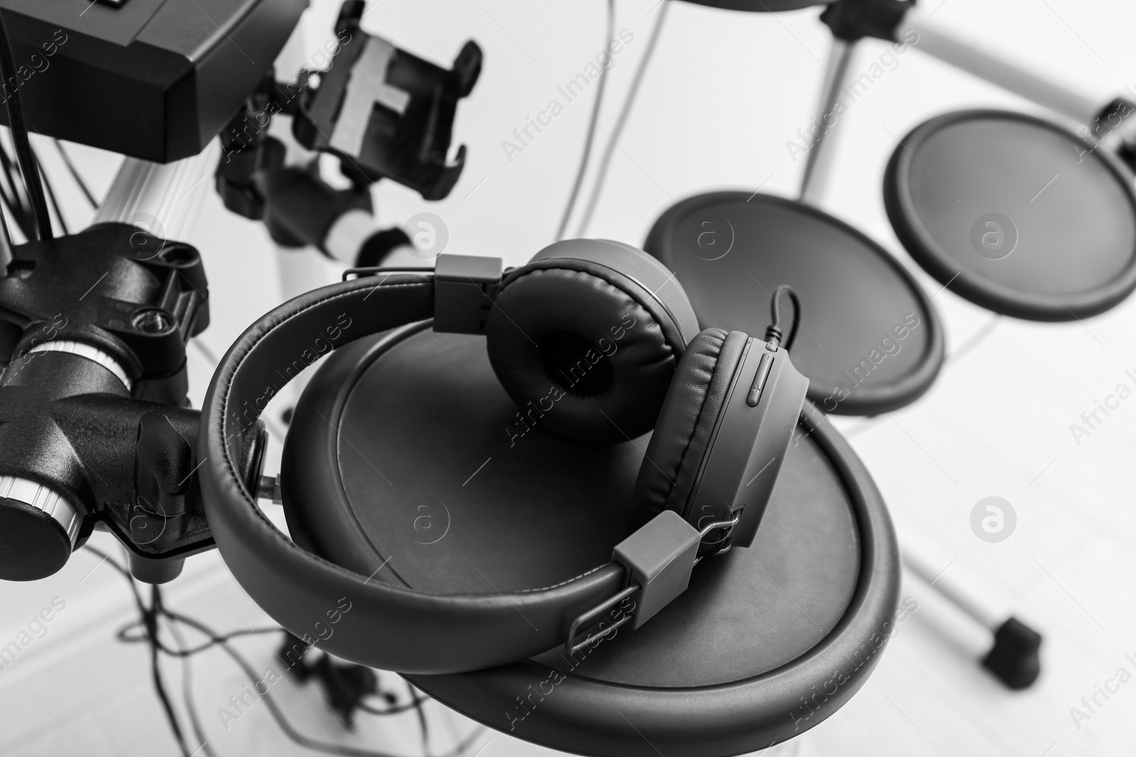 Photo of Modern electronic drum kit with headphones indoors, closeup. Musical instrument