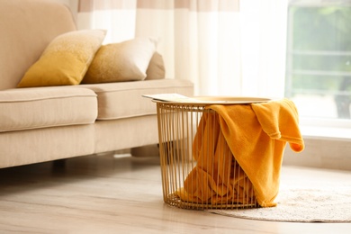 Photo of Metal basket with yellow blanket in modern room, space for text. Idea for interior design