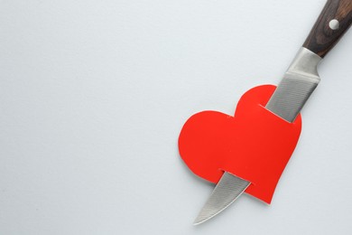 Photo of Broken heart. Red paper heart pierced with knife on white background, top view. Space for text