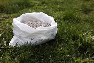 Photo of Fertilizer in bag on green grass outdoors, space for text