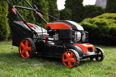 Modern lawn mower on green grass in garden