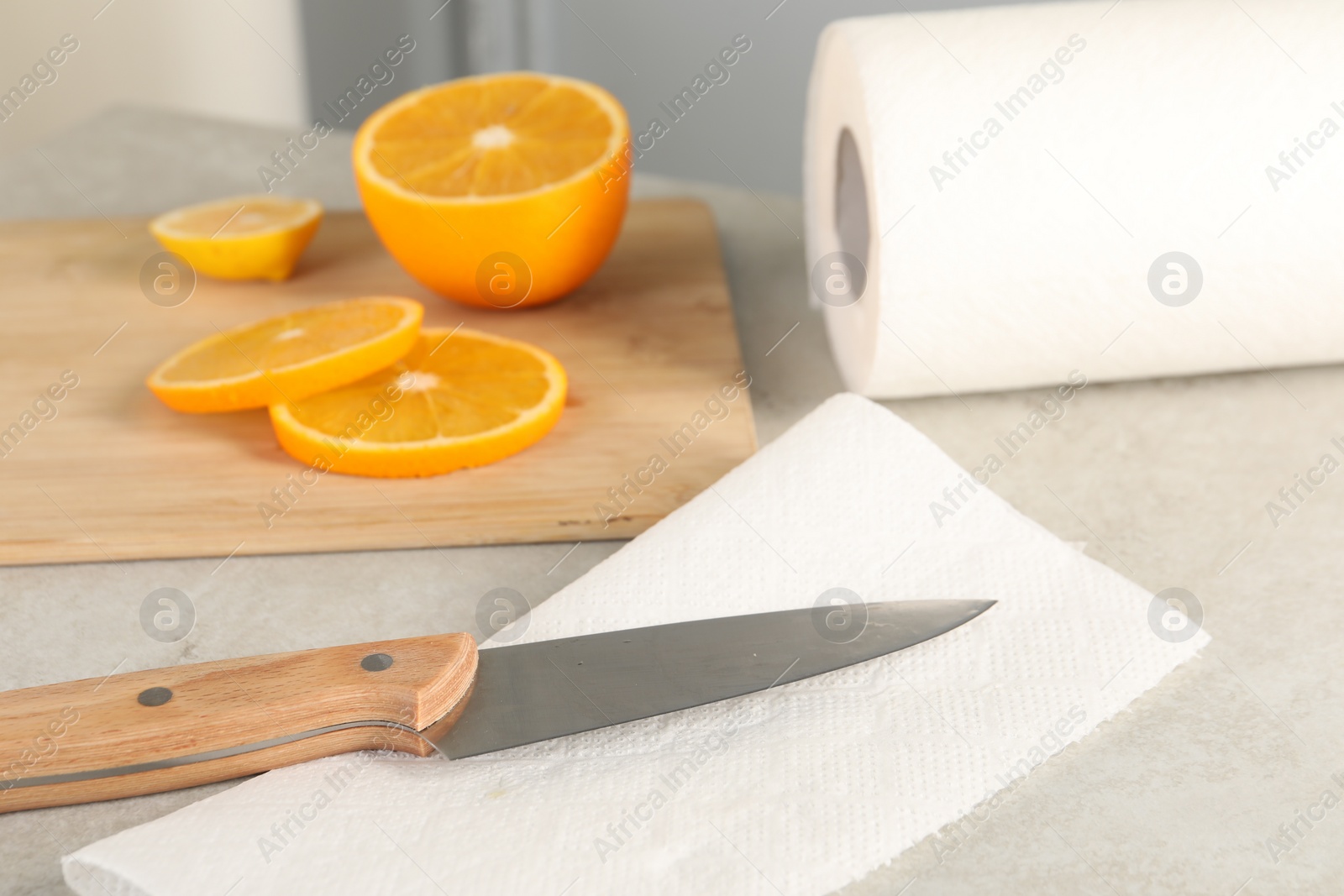 Photo of Paper towel, orange slices and knife on light table, closeup