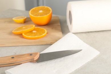 Photo of Paper towel, orange slices and knife on light table, closeup