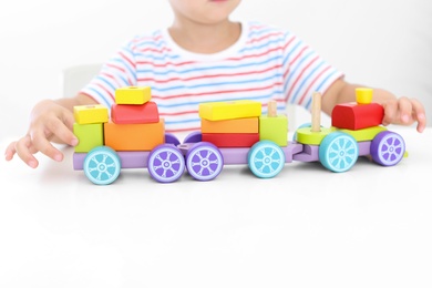 Little boy playing with toy at white table, closeup