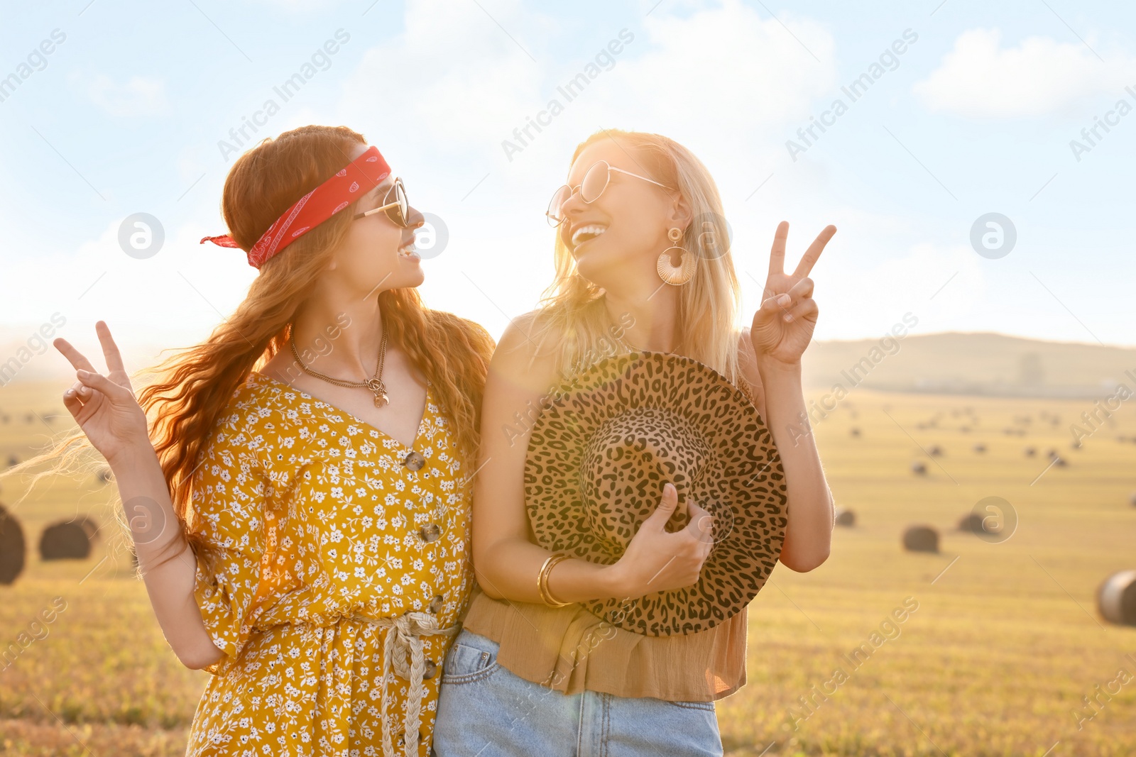 Photo of Beautiful happy hippie women showing peace signs in field