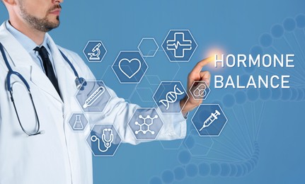 Doctor pointing at virtual screen with inscription Hormone Balance and digital icons on light blue background, closeup