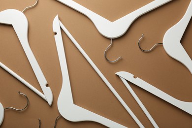 Photo of White hangers on brown background, flat lay