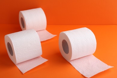 Photo of Soft toilet paper rolls on orange background