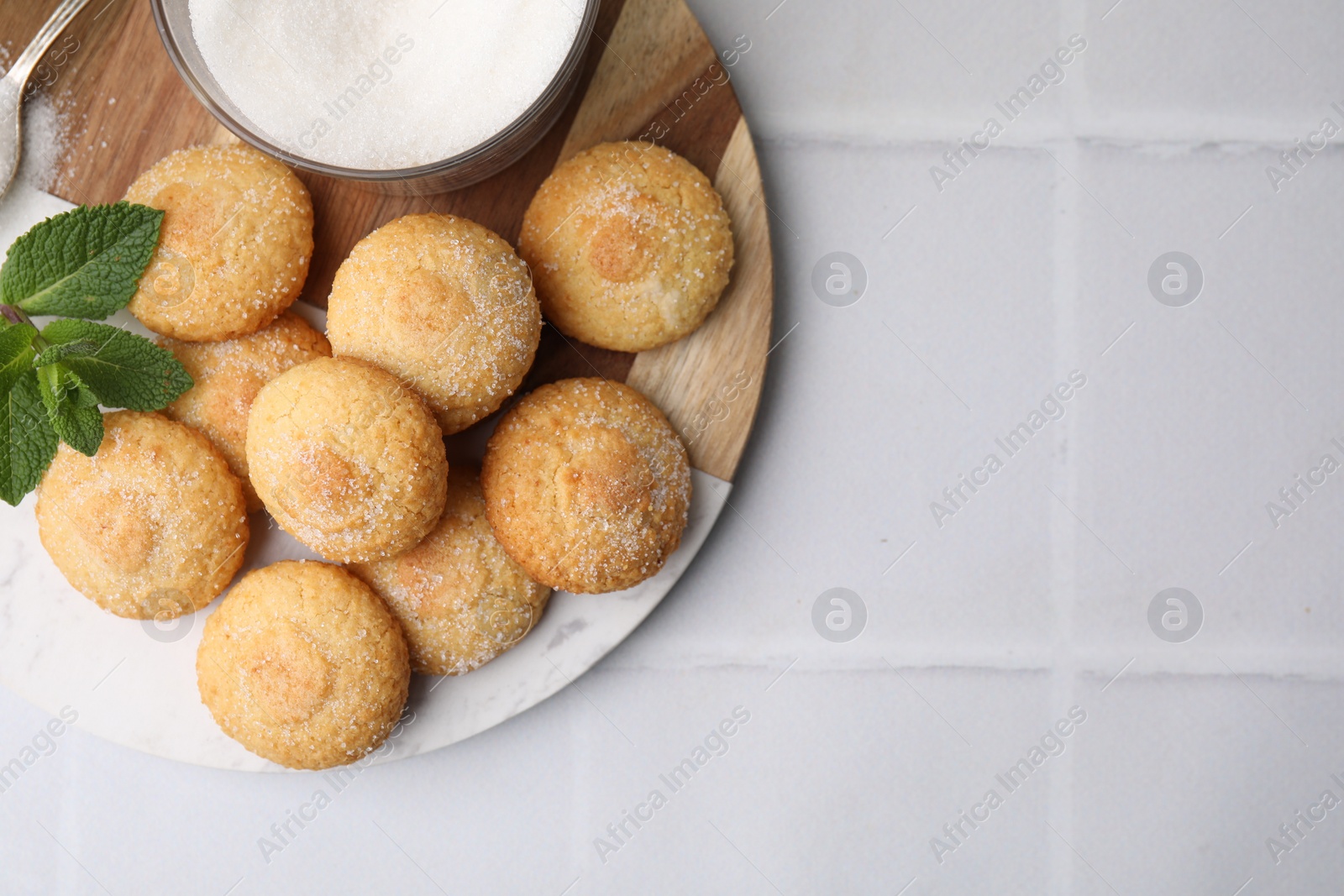 Photo of Tasty sweet sugar cookies and mint on white tiled table, top view. Space for text