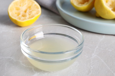 Freshly squeezed lemon juice in glass bowl on grey marble table