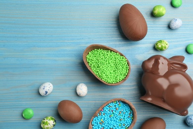 Photo of Chocolate Easter bunny and eggs on light blue wooden table, flat lay. Space for text