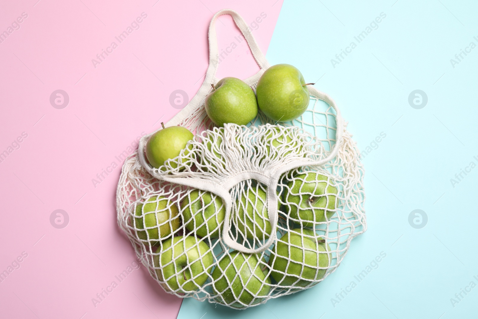 Photo of Mesh bag with ripe apples on color background, flat lay