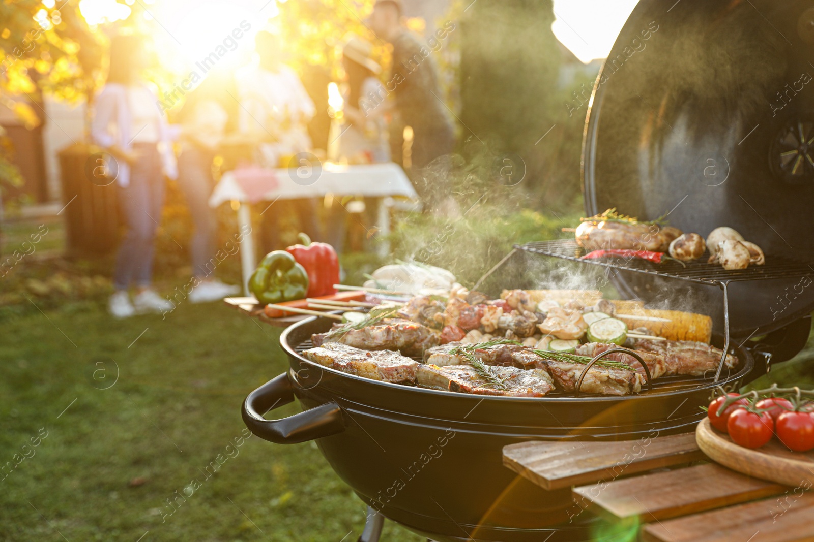 Photo of Group of friends having party outdoors. Focus on barbecue grill with food. Space for text