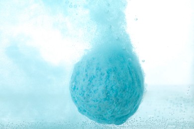 Photo of Light blue bath bomb dissolving in water, closeup
