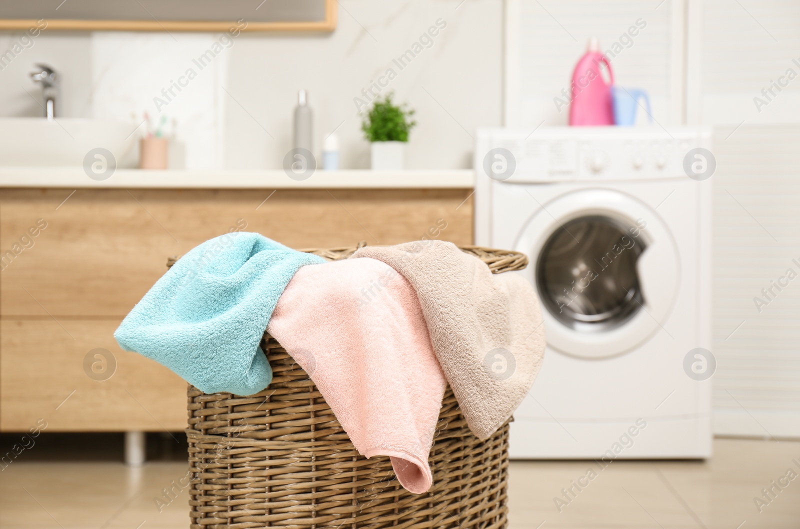 Photo of Wicker basket with laundry and washing machine in bathroom