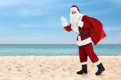 Santa Claus with sack on sandy beach. Space for text