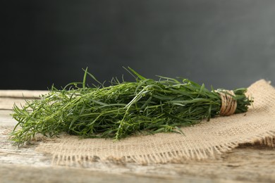 Photo of Bunch of fresh tarragon sprigs on wooden table