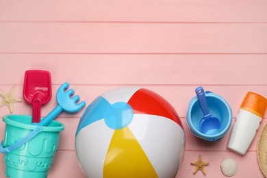 Photo of Flat lay composition with beach ball and sand toys on pink wooden background. Space for text