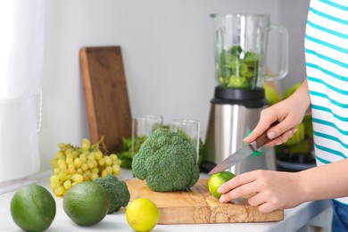 Woman cutting lime for smoothie in kitchen, closeup