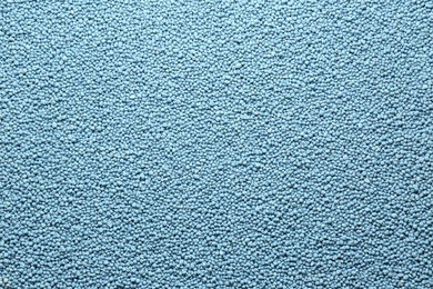 Photo of Blue granular mineral fertilizer as background, top view