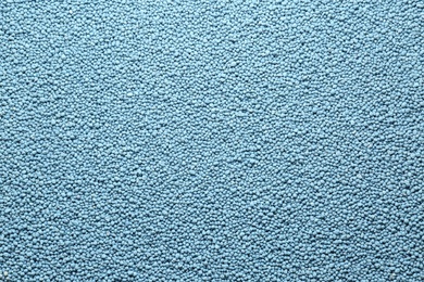 Blue granular mineral fertilizer as background, top view