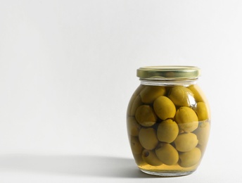 Photo of Glass jar with pickled olives on white background. Space for text