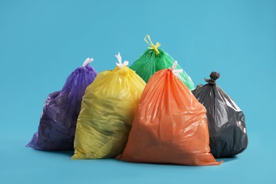 Photo of Trash bags full of garbage on light blue background