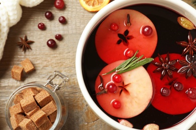 Photo of Saucepan with tasty mulled wine on wooden table, flat lay