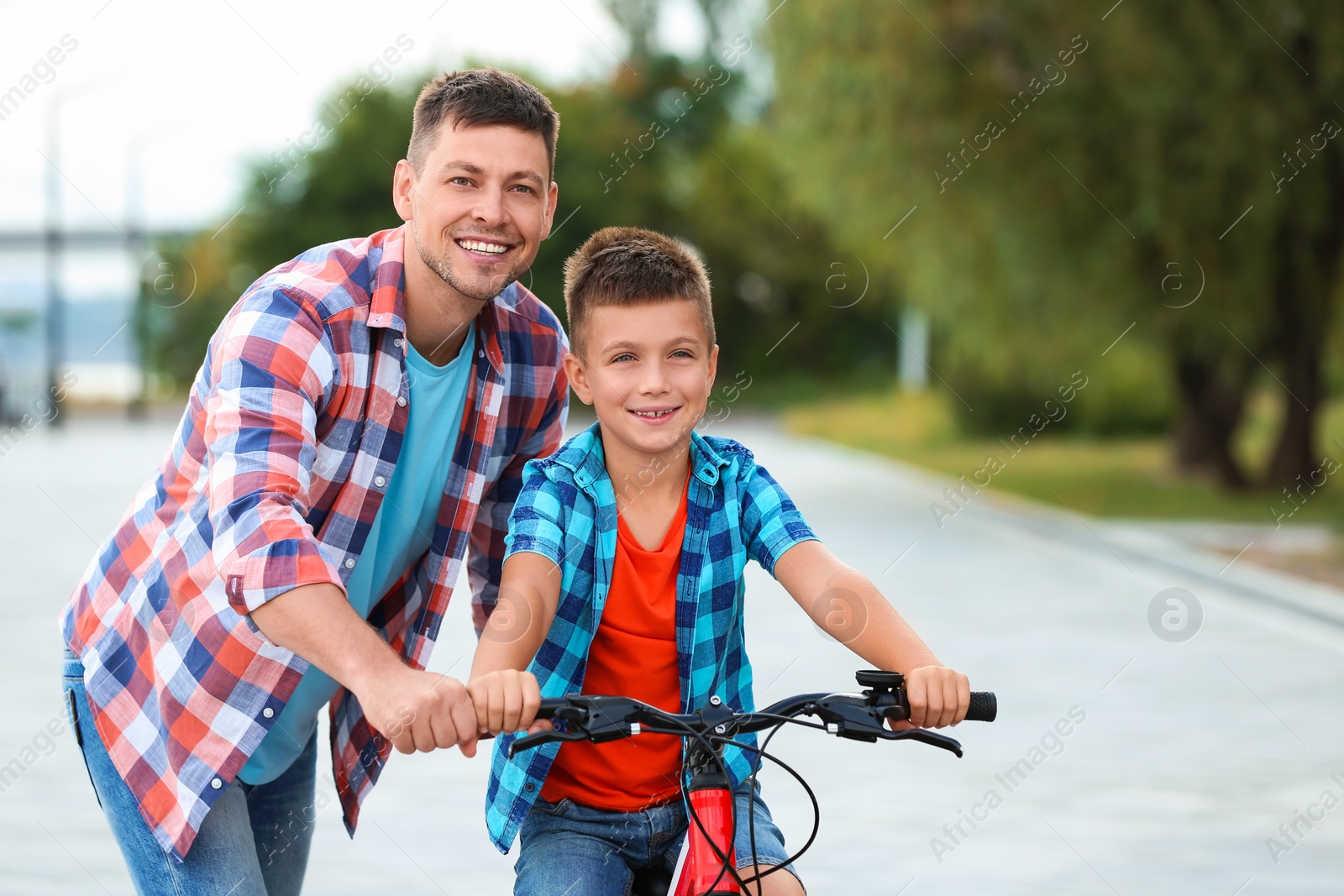 Photo of Dad teaching son to ride bicycle outdoors