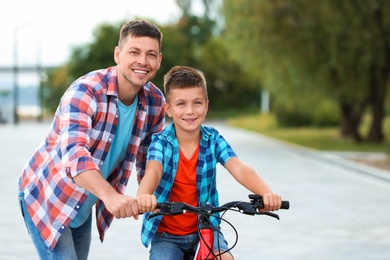 Dad teaching son to ride bicycle outdoors