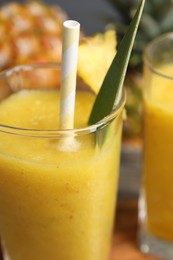 Photo of Glass of tasty pineapple smoothie on table, closeup