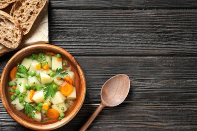 Bowl of fresh homemade vegetable soup served on dark wooden table, flat lay. Space for text