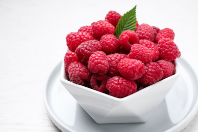 Photo of Delicious fresh ripe raspberries in bowl on white table