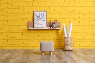 Stylish pouf near yellow brick wall indoors. Interior design