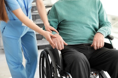 Photo of Nurse assisting senior man in wheelchair at hospital, closeup