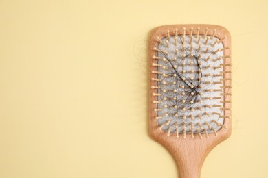 Wooden brush with lost hair on beige background, top view. Space for text