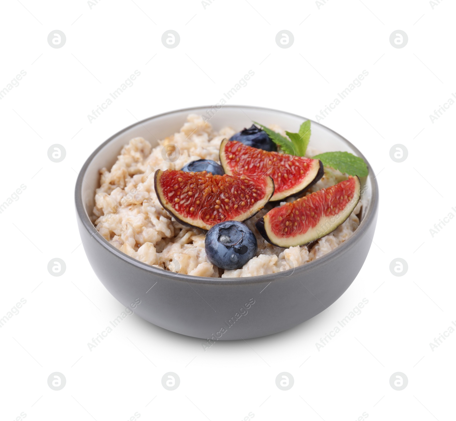 Photo of Bowl of oatmeal with blueberries, mint and fig pieces isolated on white